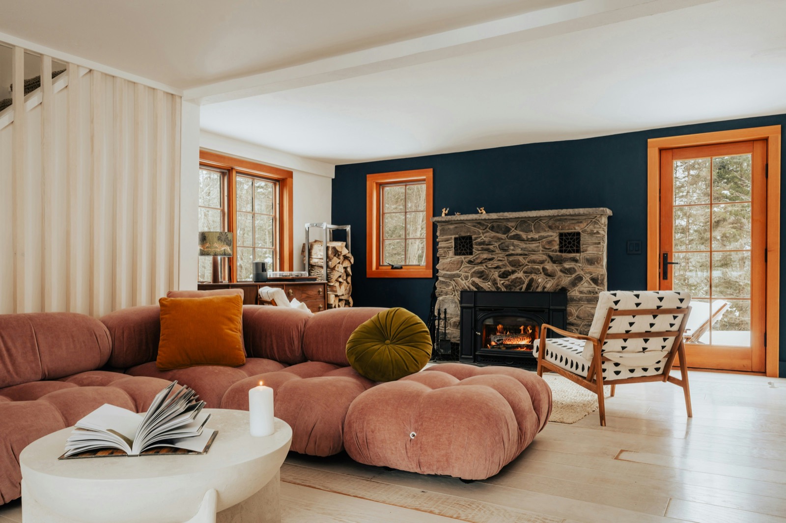 A living room with a pink sofa, a navy wall and a stone fireplace